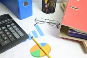 Mesa com gráficos financeiros, calculadora, lápis e pastas organizadas para análise de dados.