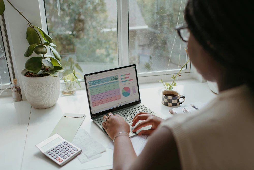 Profissional a analisar dados financeiros e relatórios num computador portátil durante a gestão financeira de uma empresa.