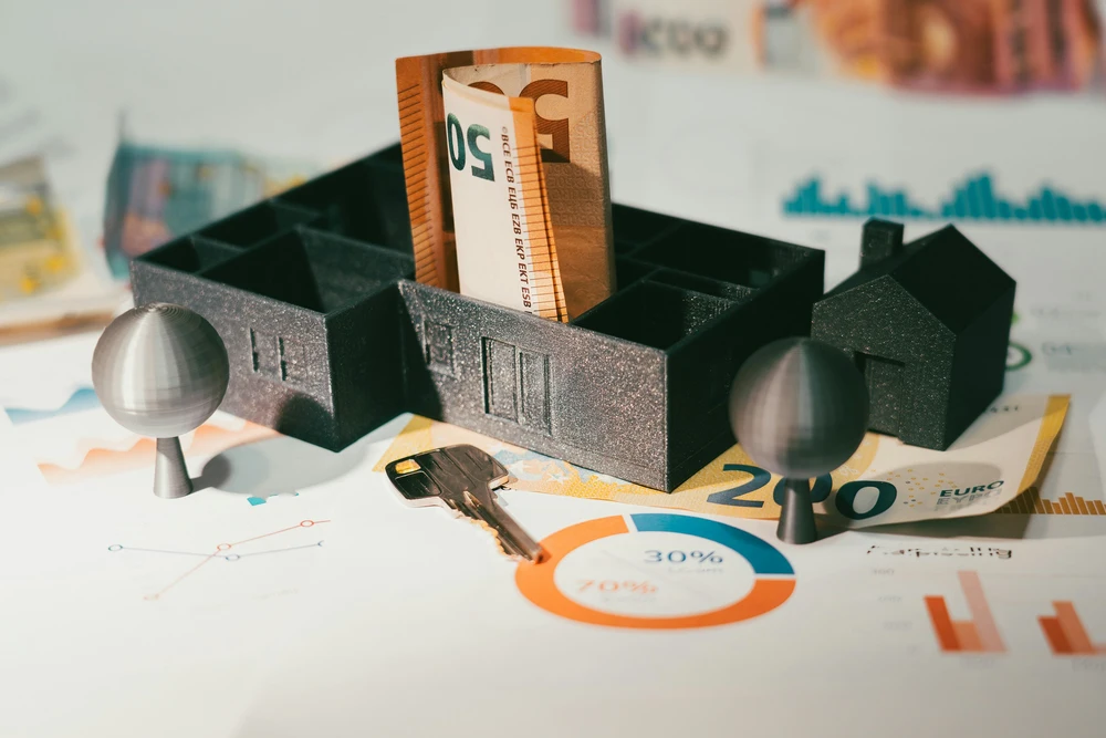 Representação de investimento imobiliário com habitação, chave, notas de euro e indicadores financeiros.